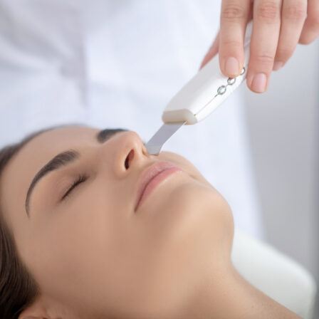 Utilisation d'un appareil de peeling à ultrason sur le visage d'une femme allongée